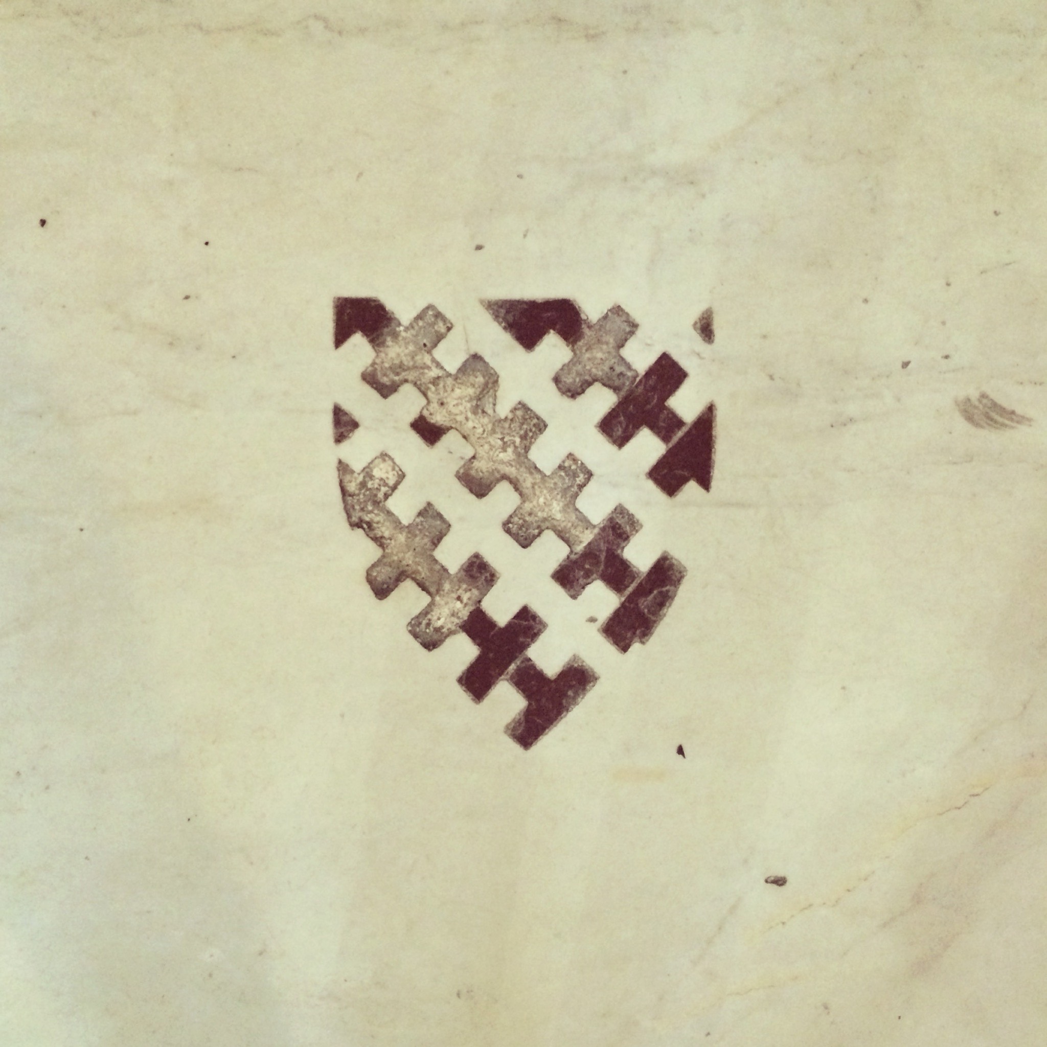 A shield with a cross-hatch pattern, inlaid in marble on the floor of San Miniato al Monte